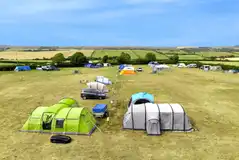 Large tents on the electric grass pitches with space for a parked car