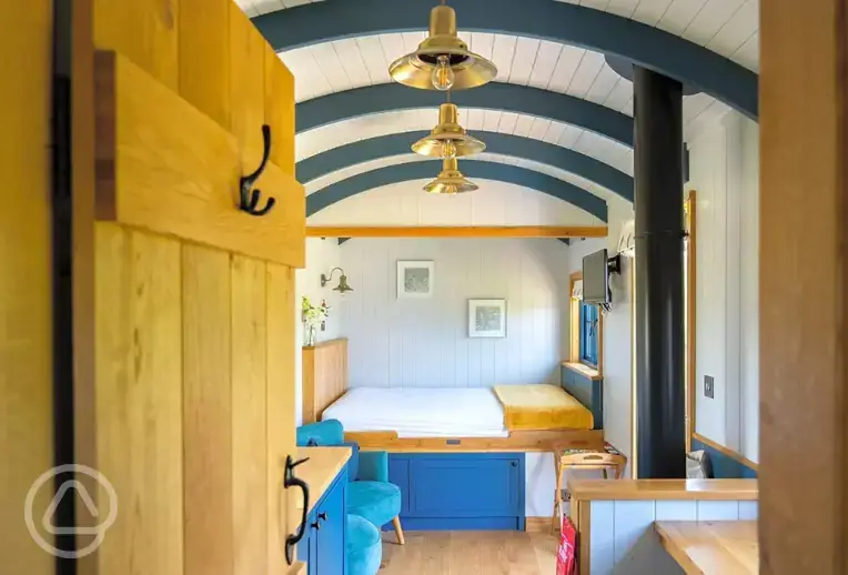 Ensuite shepherd's hut interior with double bed, kitchen and seating