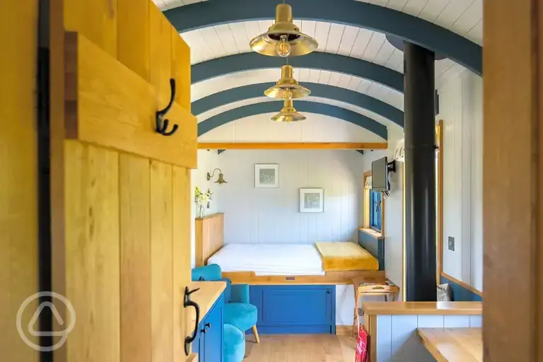 Ensuite shepherd's hut interior with double bed, kitchen and seating