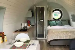 Ensuite glamping pod interior with double bed, kitchen, ensuite and dining area