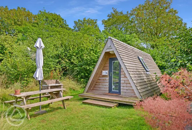 Converted chicken shed pods set amongst cob trees with outdoor seating