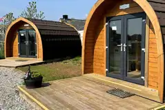 Wooden camping pods with small deck areas and glass doors