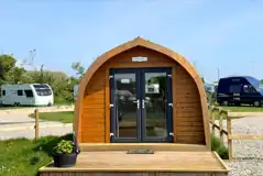 Wooden camping pod with a small deck area and glass doors