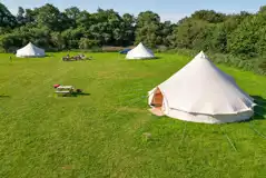 View of the furnished 7m bell tents with a picnic bench 