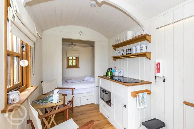 Shepherd's hut with a double bed, a micro kitchen, and furniture at Hale Farm 