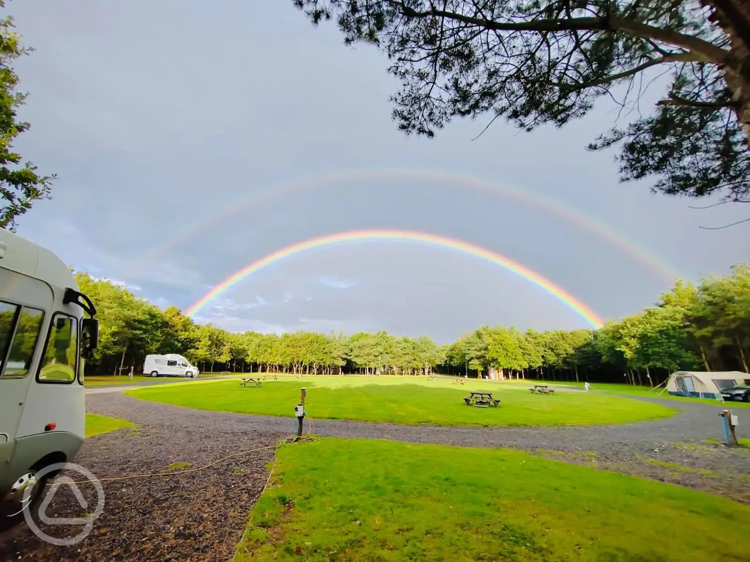 Electric hardstanding pitches overlooking a rainbow at Old Farm