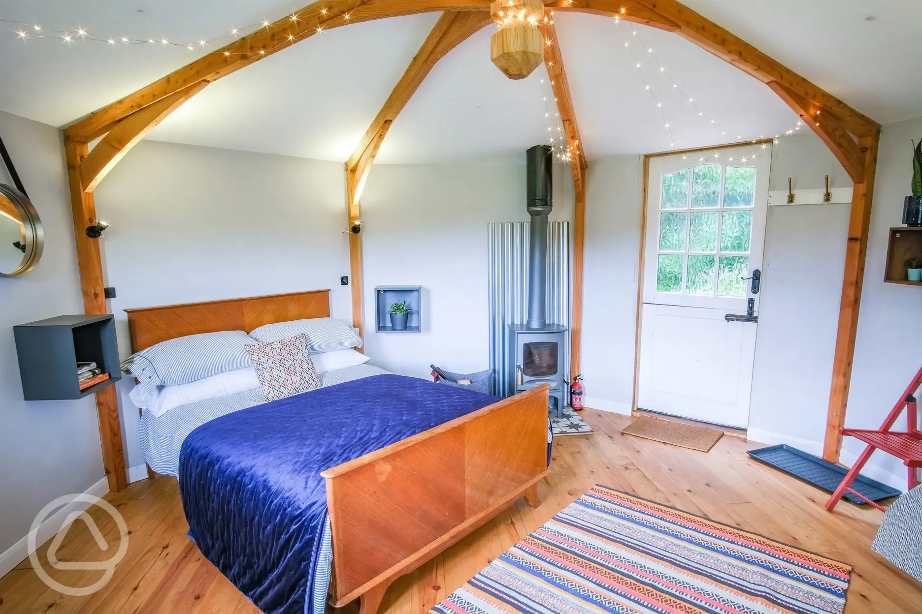Wye Glamping cabin interior with a double bed and wood burner