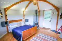 Wye Glamping cabin interior with a double bed and wood burner