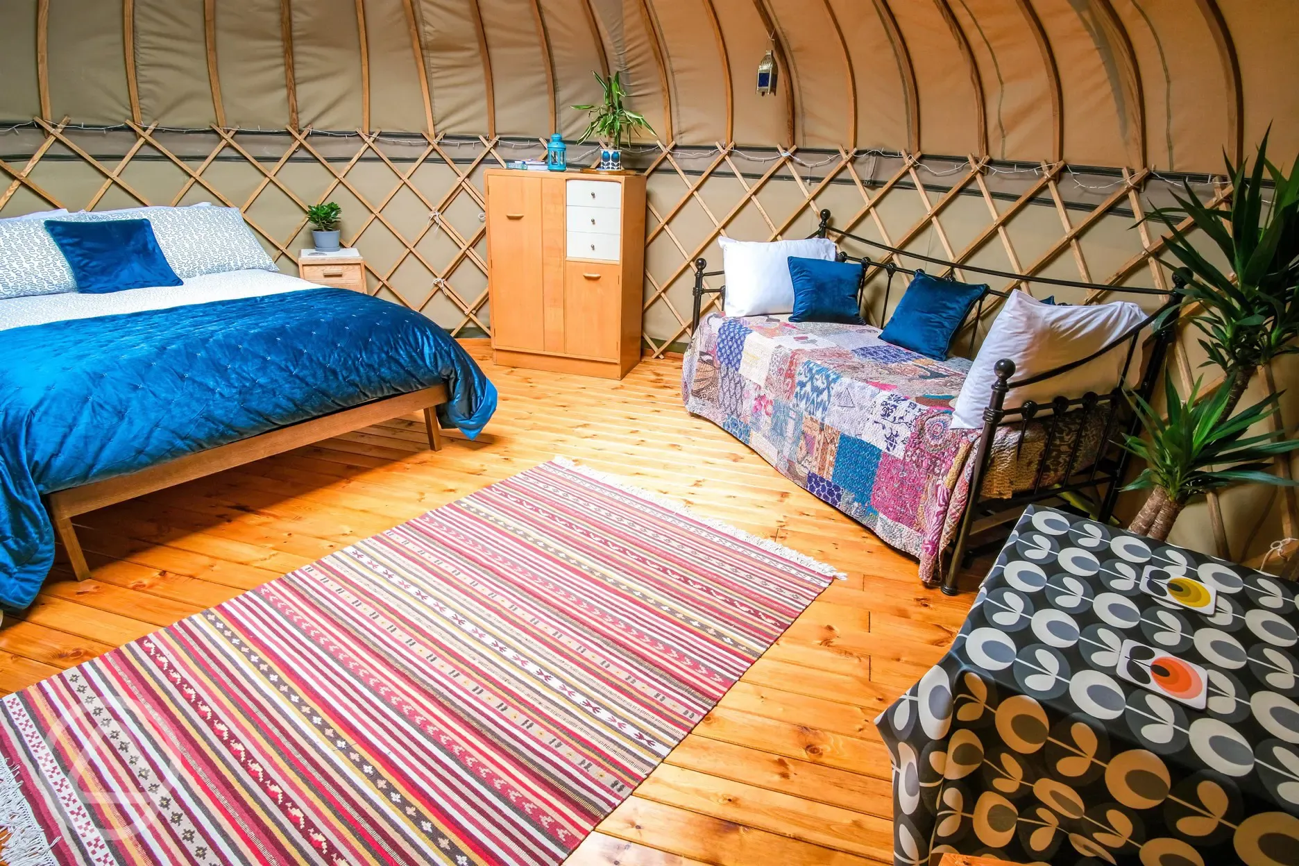 Yurt interior with a king sized bed, two single beds and soft furnishings