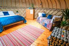 Yurt interior with a king sized bed, two single beds and soft furnishings