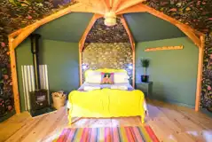 Wye Glamping cabin interior with a double bed and wood burner
