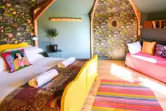 Glamping cabin interior with a double bed, two single beds and wood burner
