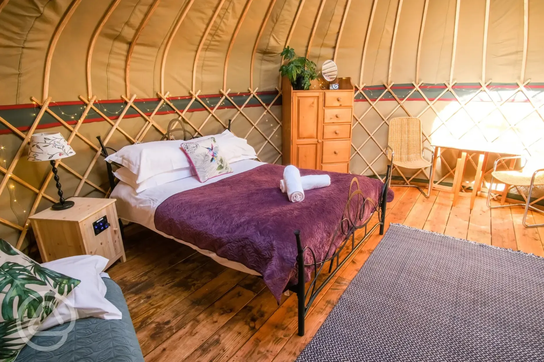 Yurt interior with a king sized bed, two single beds and soft furnishings
