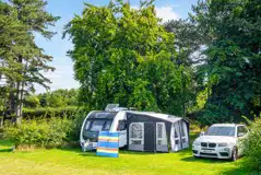 Serviced grass pitches with space for an awning and parked car