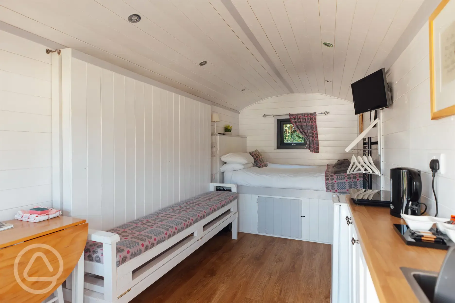 Shepherd's hut interior featuring a double bed, futon, and kitchenette