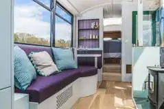 Luxury glamping bus (four person) living area with a sofa and log burner