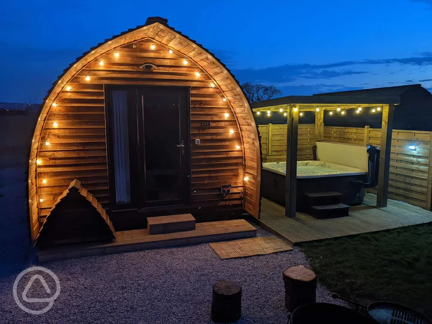 Ensuite Deluxe Wigwam Pod with wood-fired hot tub at night