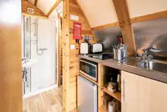 Glamping pod equipped kitchen and door to the ensuite bathroom
