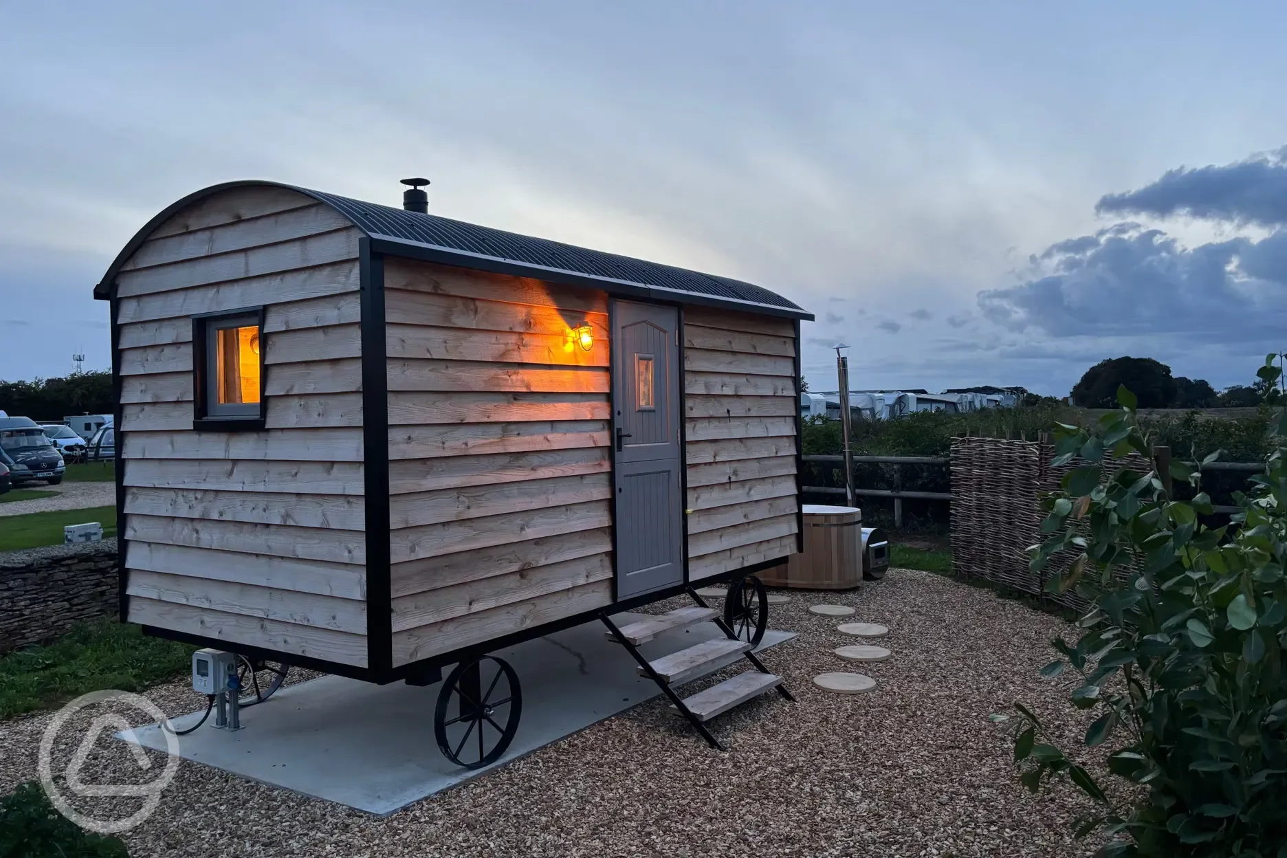 Shepherd's hut at night with outdoor wood-fired Japanese bath
