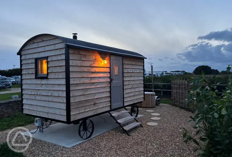 Shepherd's hut at night with outdoor wood-fired Japanese bath