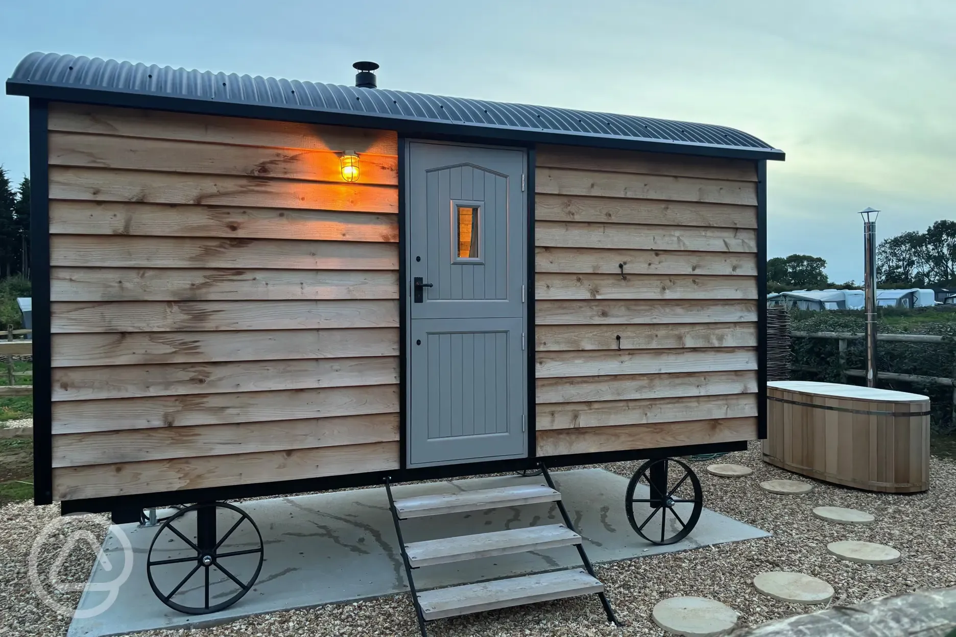 Shepherd's hut at night with outdoor wood-fired Japanese bath