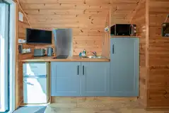 Four person pod kitchen with a fridge, microwave, sink and hob