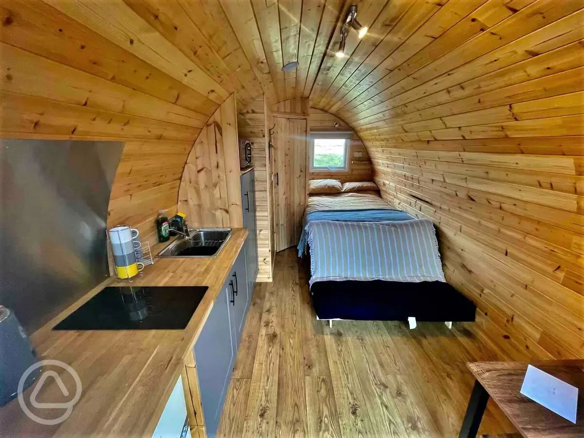 Ensuite glamping pod interior with a double bed and kitchentte at Pods Pwll Coch