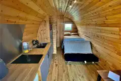 Ensuite glamping pod interior with a double bed and kitchentte at Pods Pwll Coch Ensuite glamping pod interior with a double bed and kitchentte at Pods Pwll Coch