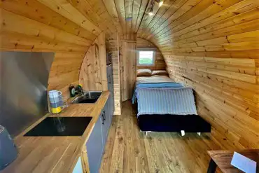Ensuite glamping pod interior with a double bed and kitchentte at Pods Pwll Coch