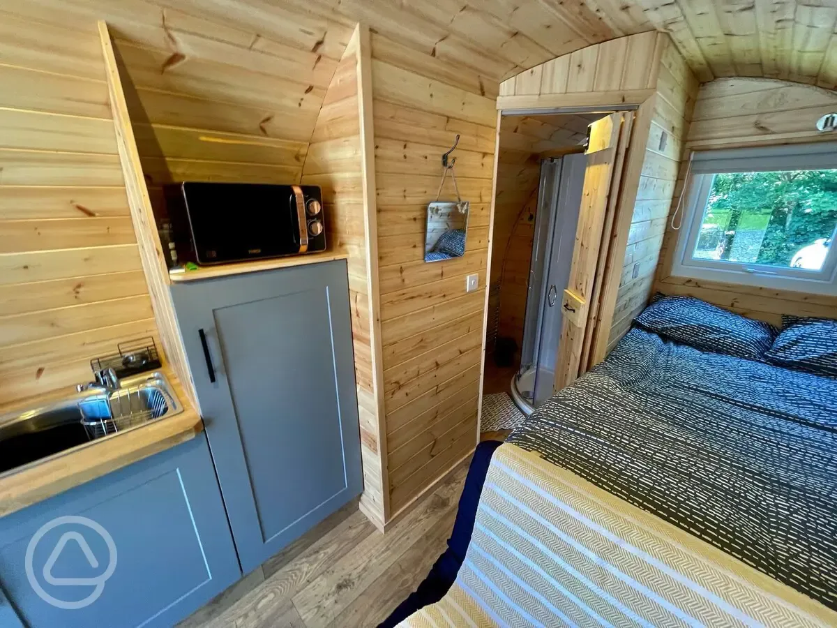 Glamping pod interior with a double bed and equipped kitchen (bedding provided)