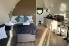 Glamping pod interior with a king size bed, kitchenette, sofa and breakfast bar