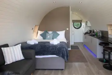 Glamping pod interior with a king size bed, kitchenette, sofa and breakfast bar