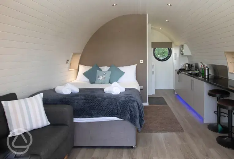 Glamping pod interior with a king size bed, kitchenette, sofa and breakfast bar