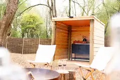 Woodland bell tent fire pit, seating and outdoor kitchen with a gas cooker