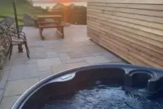 Large ensuite glamping pod hot tub and patio area at sunset Large ensuite glamping pod hot tub and patio area at sunset