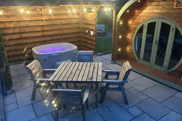 Pod at night with an electric hot tub under a pergola for shelter