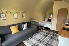 Glamping pod with hot tub interior with double bed and sofa Glamping pod with hot tub interior with double bed and sofa