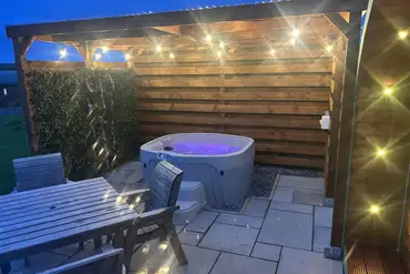 Pod at night with an electric hot tub under a pergola for shelter