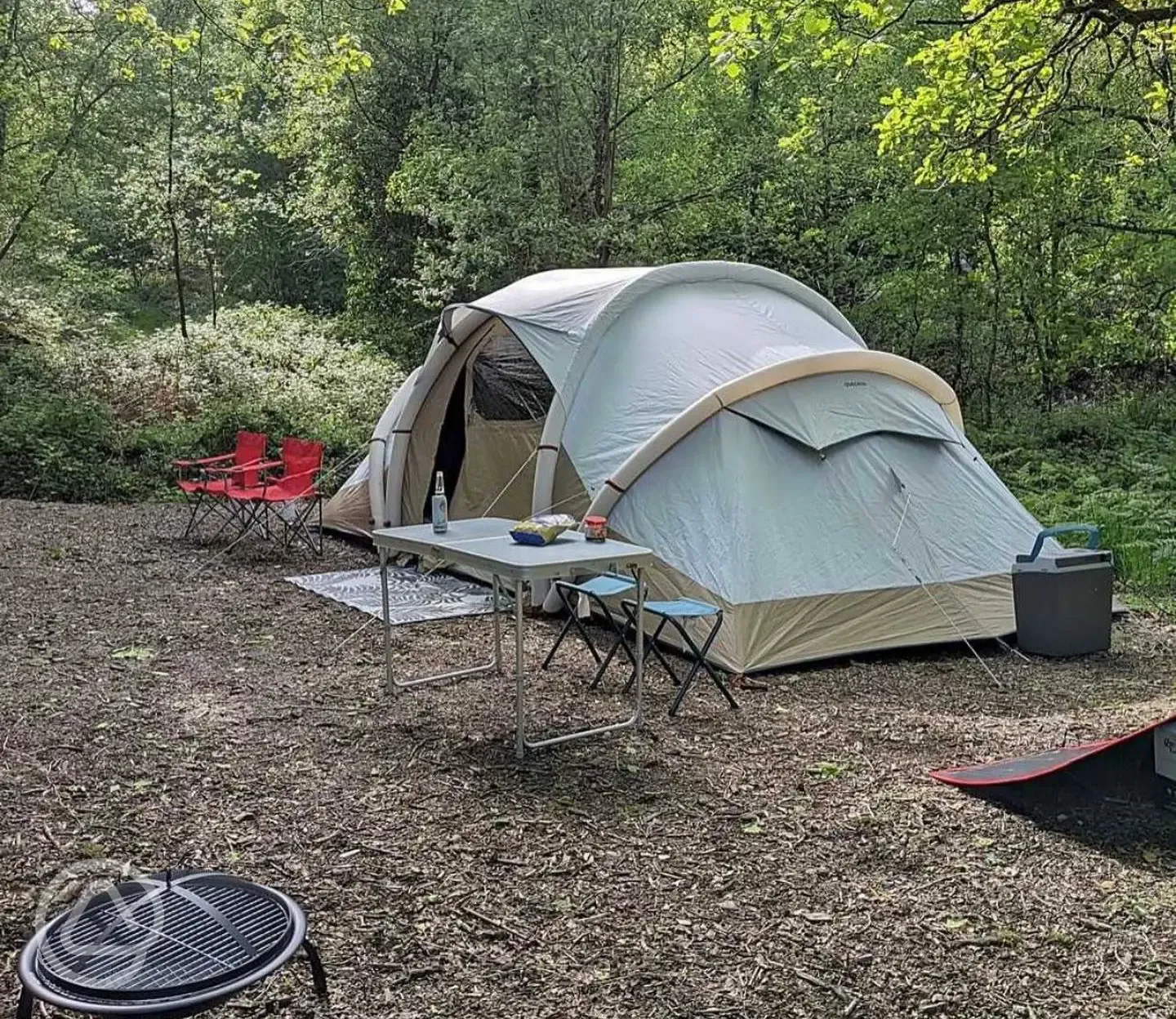 Tent on a non electric woodland tent pitch with a fold out table and chairs