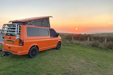 VW campervan on a grass pitch at sunset at Rainbolts Hill Farm
