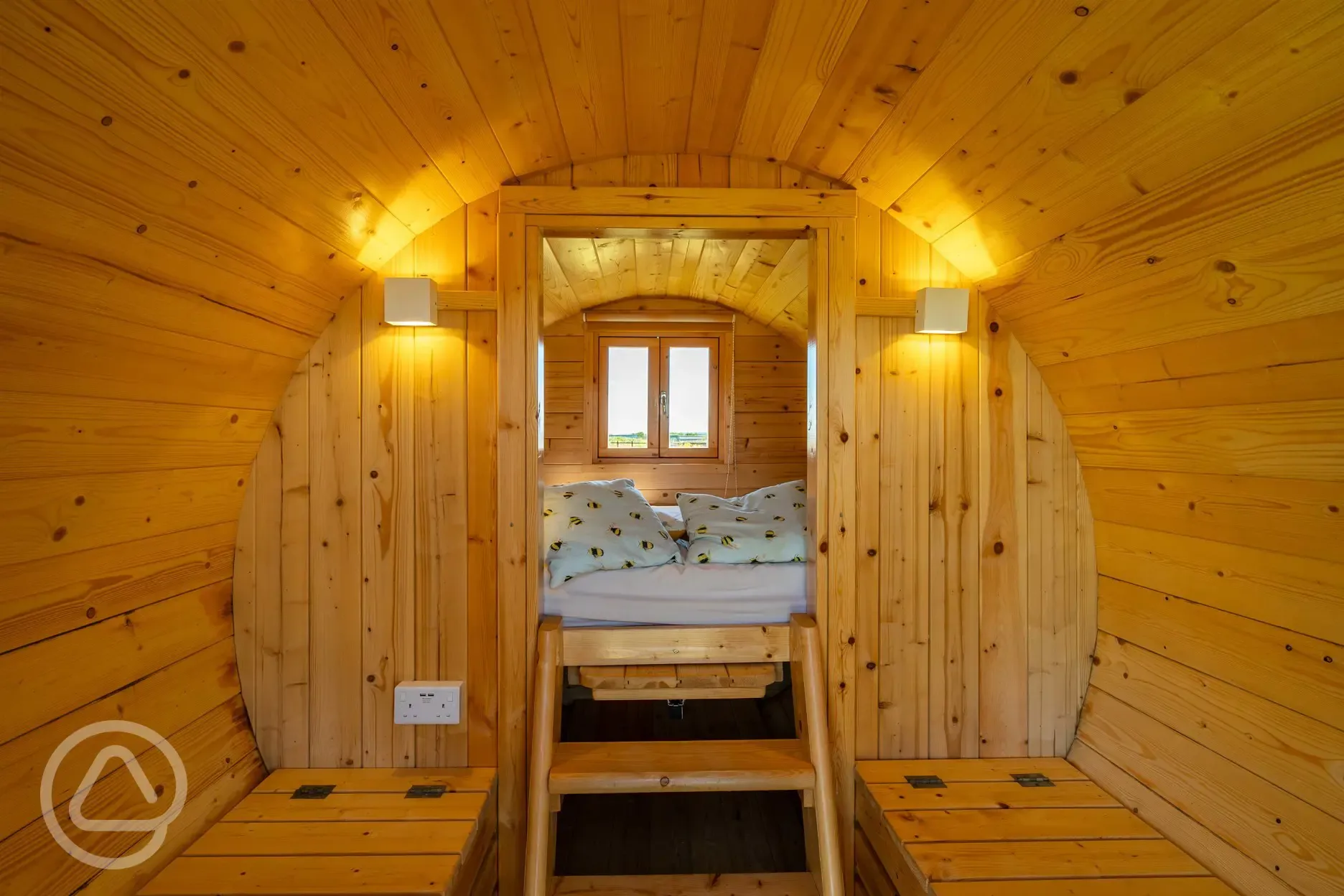 Camping pod interior with a raised bed and bench seating