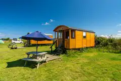 Shepherd's huts with picnic benches and umbrellas