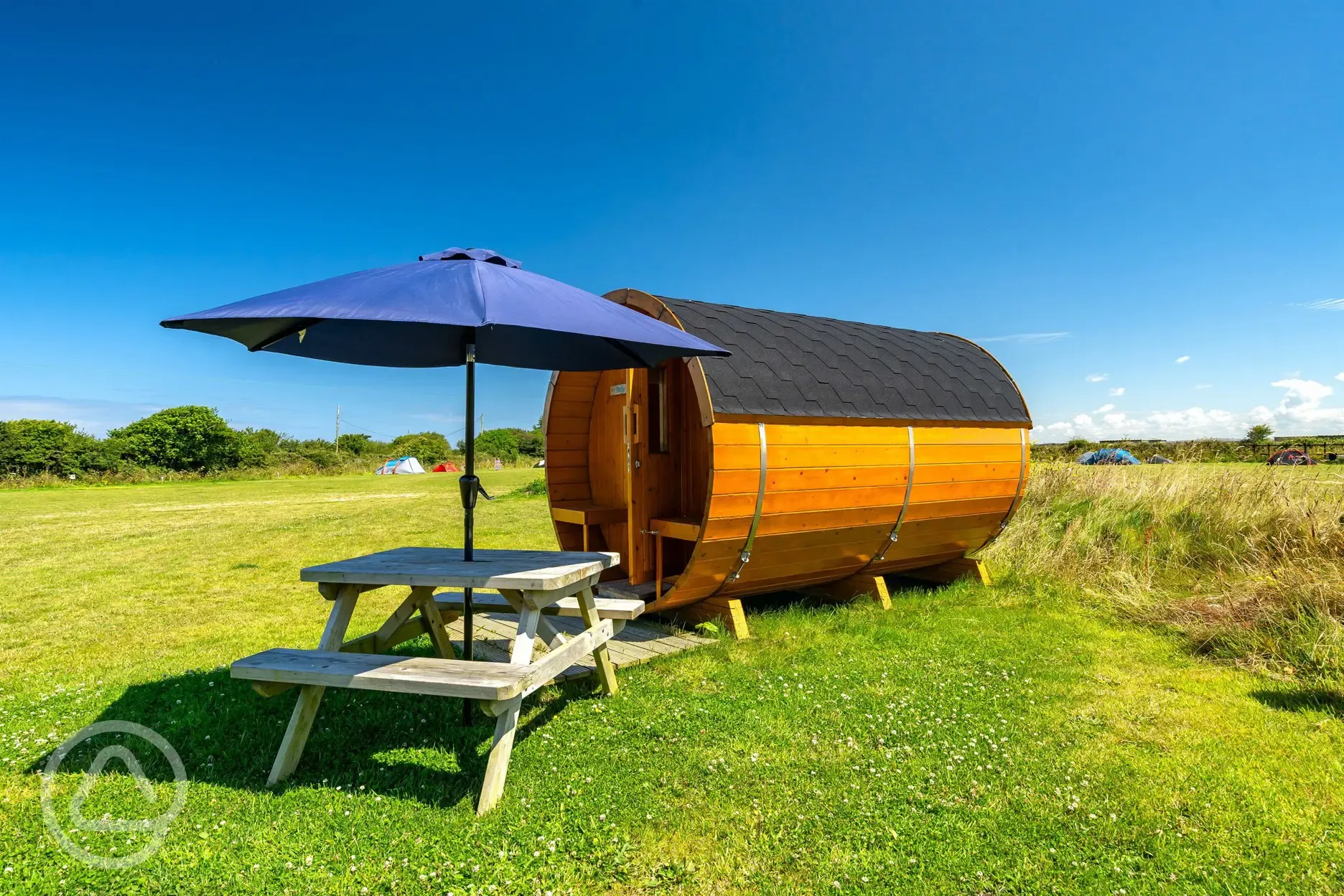 Barrel camping pod with a picnic bench and umbrella