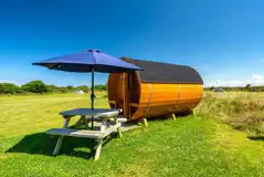 Barrel camping pod with a picnic bench and umbrella