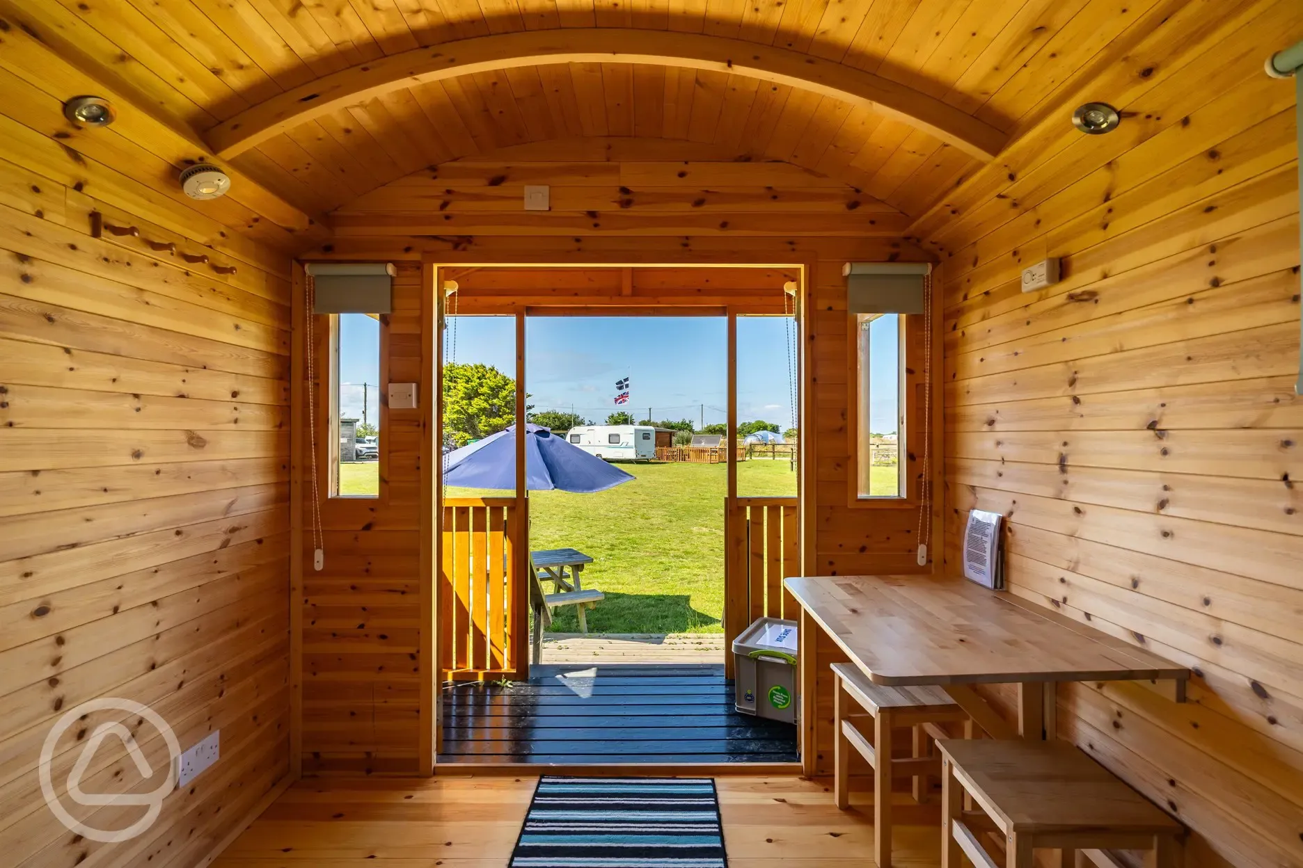 Shepherd's hut interior with a table and chairs, plus a small outdoor decking