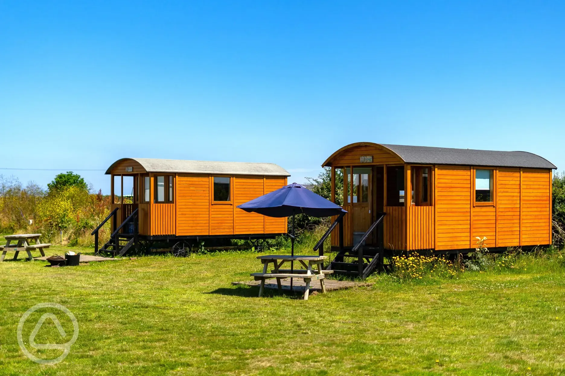 Shepherd's huts with picnic benches and umbrellas