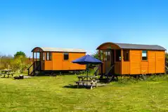 Shepherd's huts with picnic benches and umbrellas