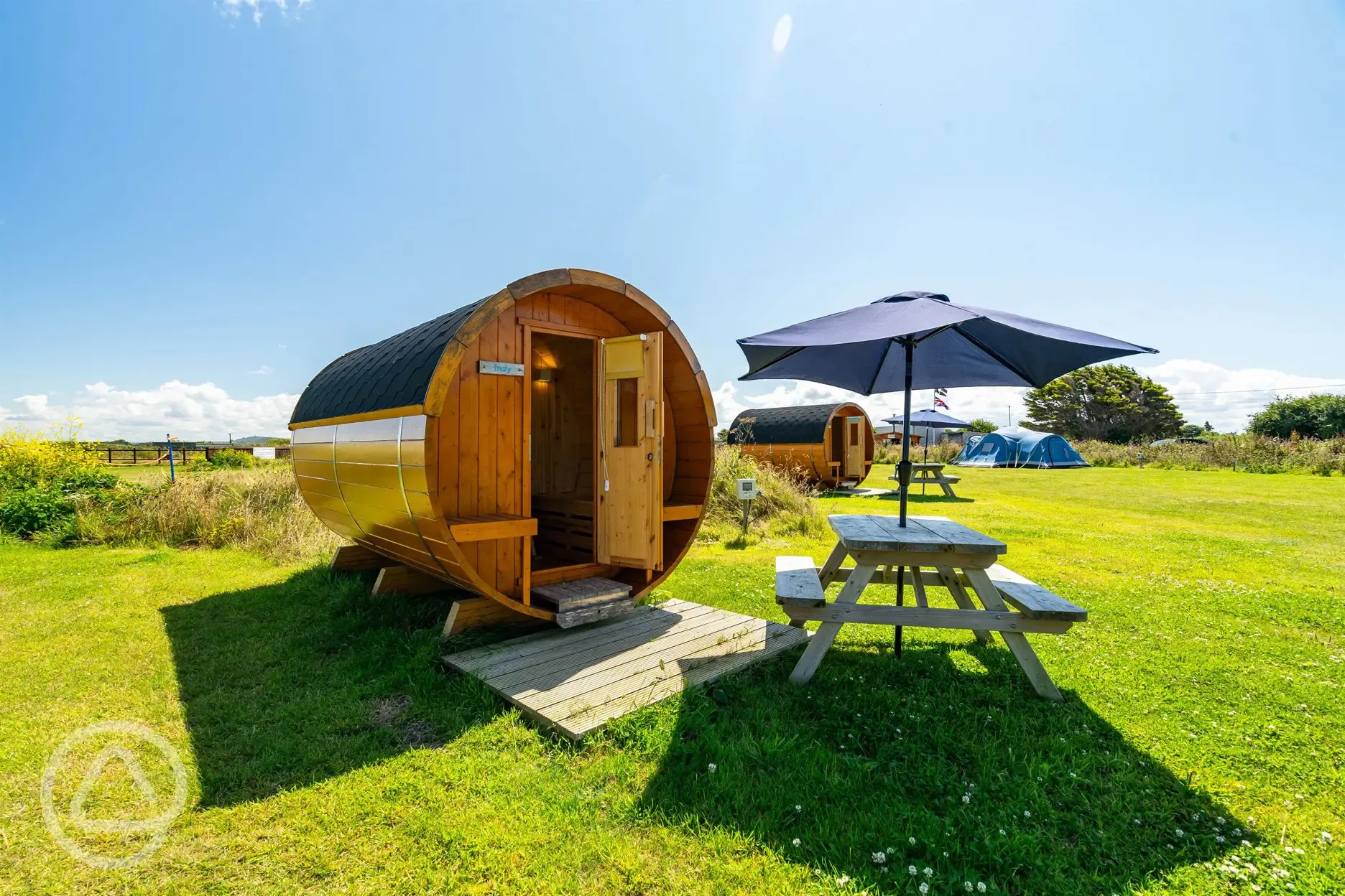 Barrel camping pod with a picnic bench and umbrella
