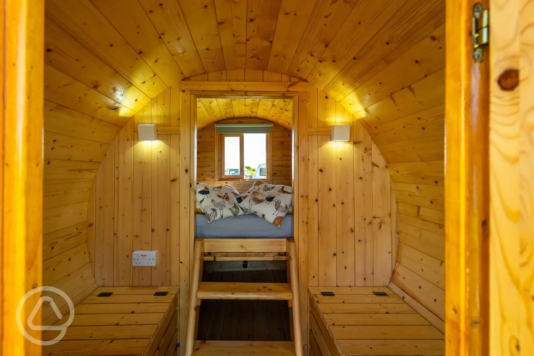 Camping pod interior with a raised bed and bench seating