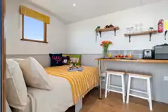 Heather shepherd's hut interior with double bed and breakfast bar